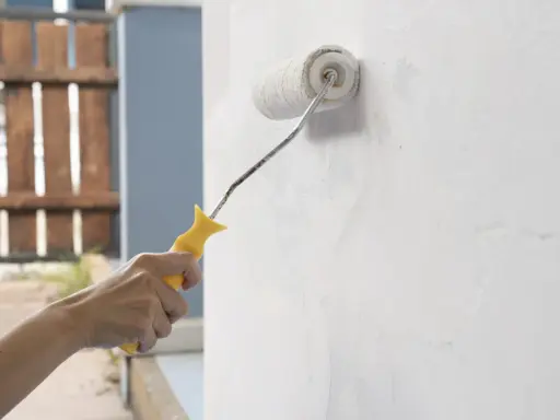 Mano aplicando imprimación a paredes con rodillo. Preparando la superficie para pintar.