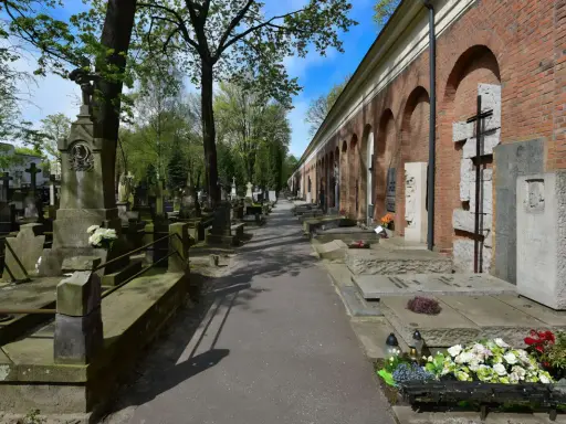 Aleja przez zabytkową nekropolię z nagrobkami i mauzoleami wzdłuż ceglanego muru z arkadami.
