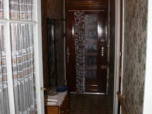 Couloir d'une maison bordeaux typique, avec une porte en bois, un porte-manteau et un papier peint fleuri.