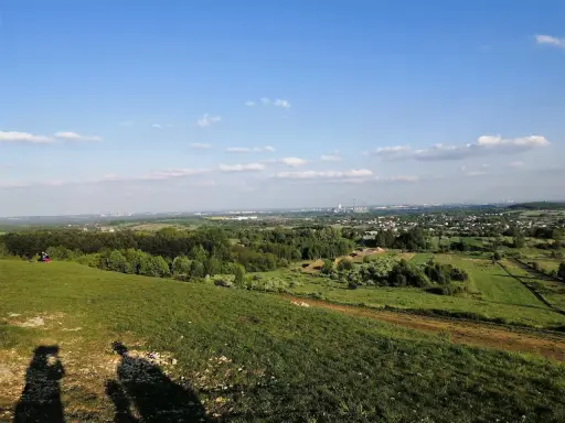Widok z góry Siewierskiej na zielone pola i lasy, w oddali widać zabudowania i kominy.