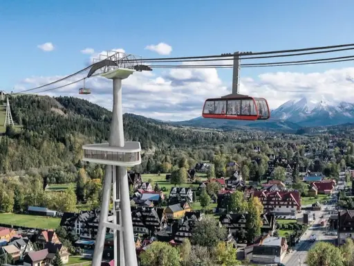 Nowe atrakcje Białki Tatrzańskiej i okolice: kolejka linowa z widokiem na Tatry, nowoczesna wieża widokowa i malownicze domy.