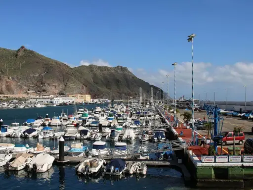 Viele Boote liegen im Hafen von Teneriffa vor Anker, im Hintergrund erheben sich grüne Berge.
