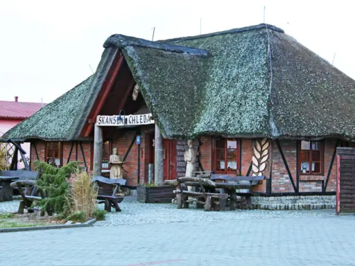 Skansen chleba z charakterystycznym, strzechą krytym dachem. Drewniane ławy i stoły zapraszają do odpoczynku.