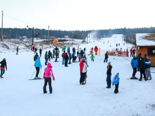 Ludzie jeżdżą na nartach i snowboardach, ciesząc się zimowymi atrakcjami. Warunki na stokach wydają się dobre, śnieg jest obecny, a pogoda sprzyja aktywnościom na świeżym powietrzu.