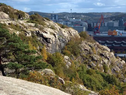 Steniga sluttningar med träd och buskar i Keillers park, med Göteborgs stad och hamnen i bakgrunden.