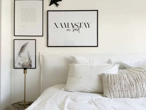 Un lit douillet avec une tête de lit DIY, des coussins texturés et des cadres muraux inspirants.