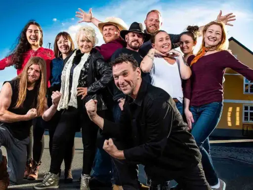 En glad grupp svenskar, kanske från en historia podd med Anders Lundin, poserar glatt utomhus.