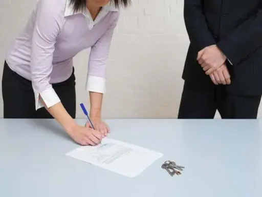Une femme signe un document, peut-être un passage expert assurance habitation, tandis que des clés reposent sur la table.
