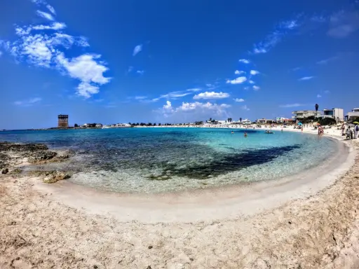 Spiaggia incantevole nel Salento ionico, con acque cristalline, sabbia dorata e un'antica torre di avvistamento.