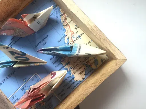 Kreative **Geldscheine falten** zu Schiffen, die auf einer Karte der norwegischen See segeln. Eine **muschel**-förmige Faltung ist nicht zu sehen, aber die Origami-Boote sind detailreich.