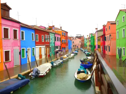 Venise : une maison colorée et d'autres maisons aux teintes vives bordent un canal où flottent des bateaux.