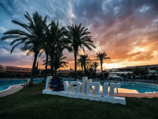 Tramonto infuocato sul Valtur Calabria Otium Resort. Palme e piscina creano un'atmosfera da sogno.