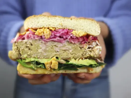 Hamburguesa de pollo con aguacate, col morada y crujientes trozos. ¡Una delicia!