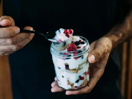 Ein Glas Magerquark mit Beeren, perfekt für den Muskelaufbau. Eine Löffelspitze voller Genuss.