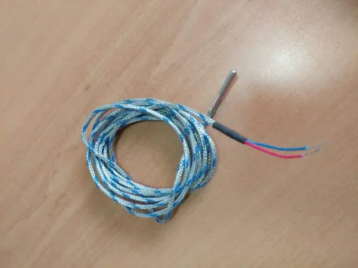 Sonda de temperatura para estufa de pellets, posiblemente indicando un fallo. Cable enrollado con punta metálica y cables rojo y azul.