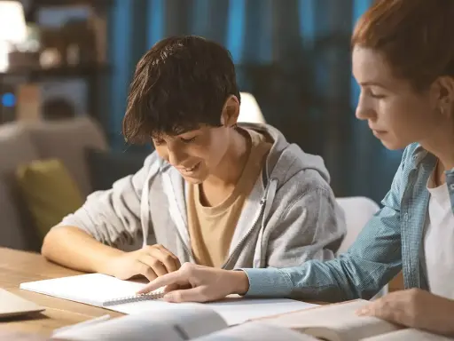 Ein Schüler gibt einem jüngeren Jungen Nachhilfe. Beide sind konzentriert und lernen gemeinsam.