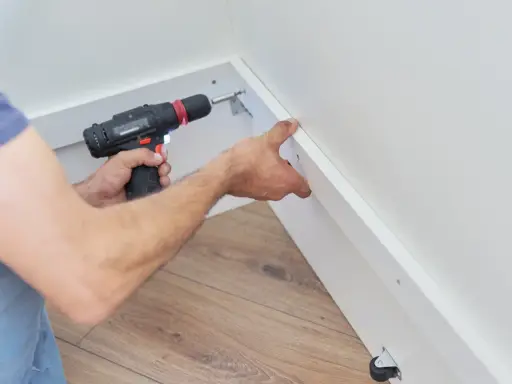 Pose d'une placo sur ossature bois. Un artisan utilise une visseuse pour fixer une plaque de plâtre sur une structure en bois.