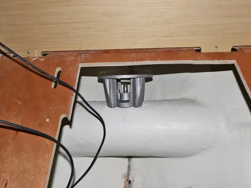 Installation d'un propulseur d'étrave : pièce métallique argentée fixée dans une ouverture, câbles noirs visibles.