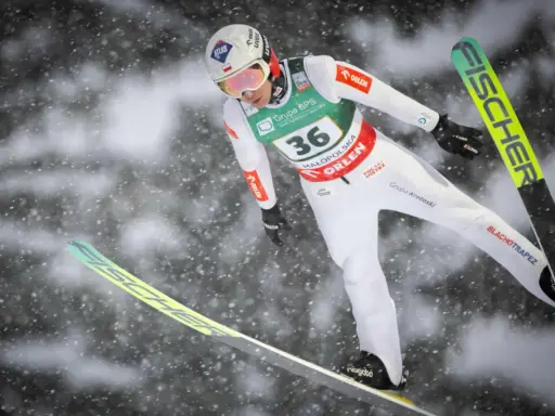 Skoczek narciarski w locie, przygotowuje się do lądowania. Widoczny numer 36. To może być zapowiedź skoki narciarskie 2026.