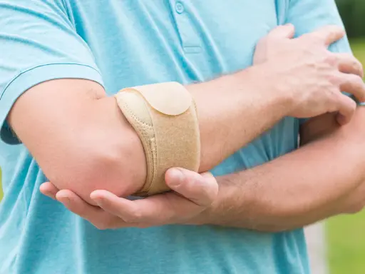 Mann mit Bandage am Ellenbogen, um Schmerzen bei Tennisarm zu lindern.