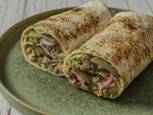 Zwei saftige Big Mac Wraps mit Hackfleisch, Salat, Gurken und Zwiebeln auf einem grünen Teller.