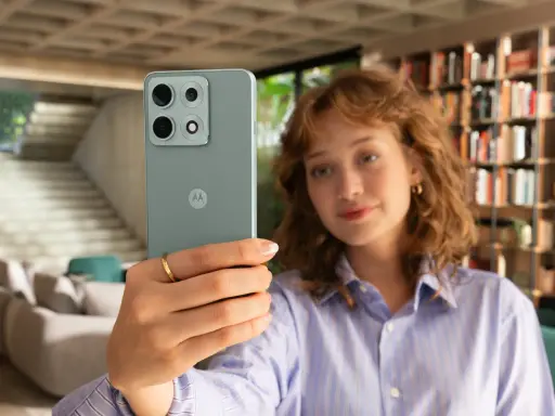 Kobieta robi selfie telefonem Motorola E6 Play w nowoczesnym wnętrzu.