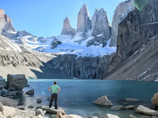 Widok na majestatyczne Torres del Paine w Chile. Turysta podziwia turkusowe jezioro i ośnieżone szczyty.