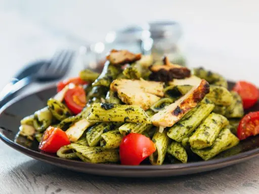 Penne z kurczakiem i pomidorkami, obficie polane aromatycznym makaronem z pesto bazyliowym. Pyszny obiad gotowy!