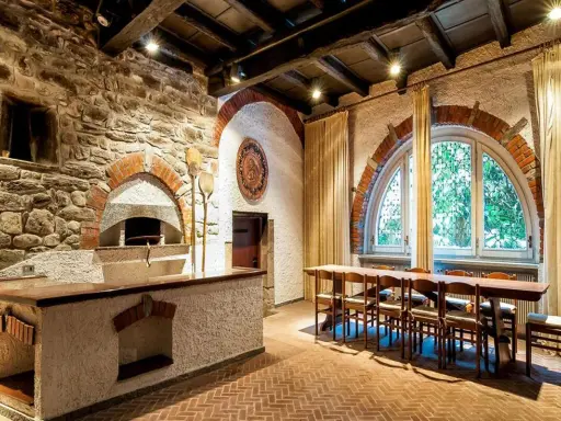 Tavernetta moderna piccola con forno a legna in pietra, bancone in muratura e un lungo tavolo in legno con sedie.