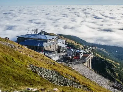 Widok na Kasprowy Wierch szlak z kolejką linową i budynkami, nad morzem chmur.