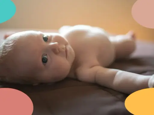 Un bebé de 2 meses, con ojos curiosos, yace boca arriba. Parece que este pequeño no duerme, ¡sus ojitos están bien abiertos!