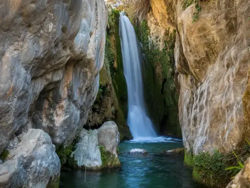 Cascada cayendo en pozas cristalinas, un rincón idílico de piscinas naturales Alicante.