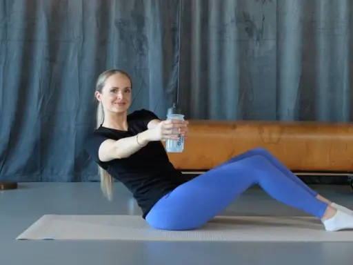 Frau macht isometrisches Krafttraining mit einer Wasserflasche, trainiert den Rumpf und die Bauchmuskeln.