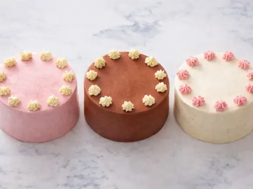 Trois petits gâteaux décorés, parfaits pour une recette de bento cake. Un rose, un chocolat, un vanille.