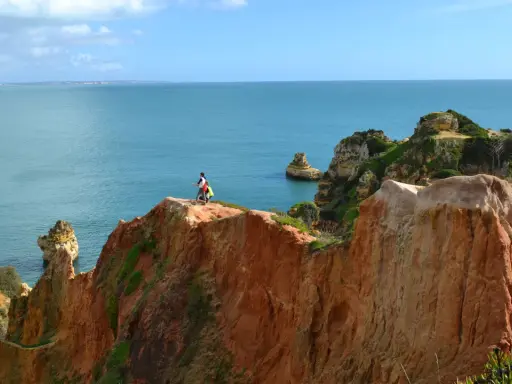 Zwei Wanderer genießen die milden Temperaturen Portugals im November an einer Klippe mit Blick auf das Meer.