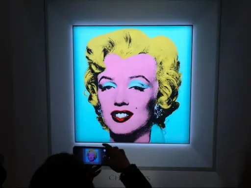 A person photographs Andy Warhol's iconic Marilyn Monroe printmaking, capturing the vibrant colors and pop art style.