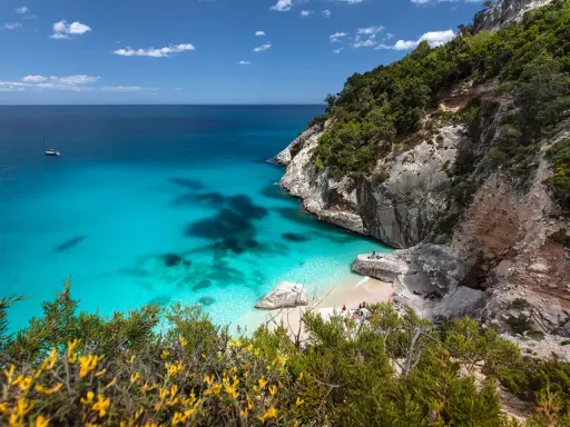 Traumhafter Strand Sardinien mit türkisfarbenem Wasser, Felsen und grüner Vegetation. Eine kleine Bucht lädt zum Entspannen ein.