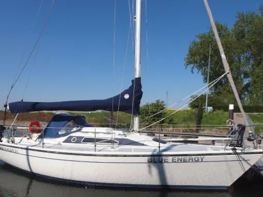 Weiße Segelyacht "Blue Energy" mit blauem Segel, liegend am Steg. Interessante dehler 31 technische daten für Segelfreunde.