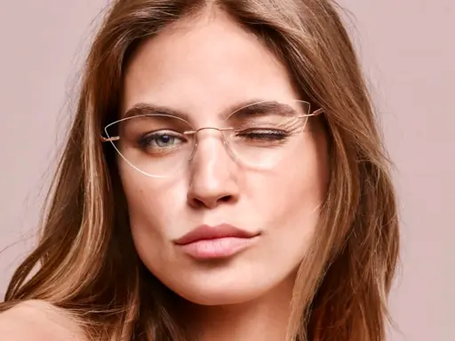 Eleganckie okulary korekcyjne bez oprawek podkreślają spojrzenie kobiety, która mruga do obiektywu.