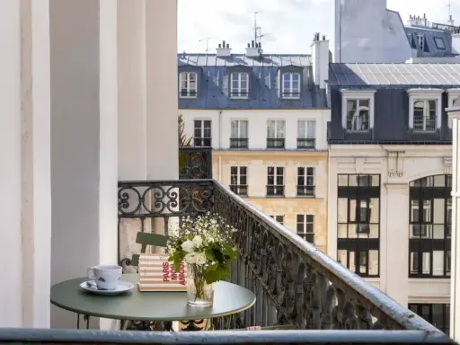 Petit-déjeuner sur le balcon avec vue sur les toits de Paris. Une tasse de café, un livre "Paris mon amour" et des fleurs, un moment de détente au saint-grégoire.