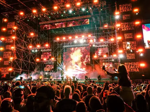 Un concerto elettrizzante alla Rimini Beach Arena. Migliaia di fan in delirio sotto un palco imponente illuminato da luci stroboscopiche e schermi giganti.