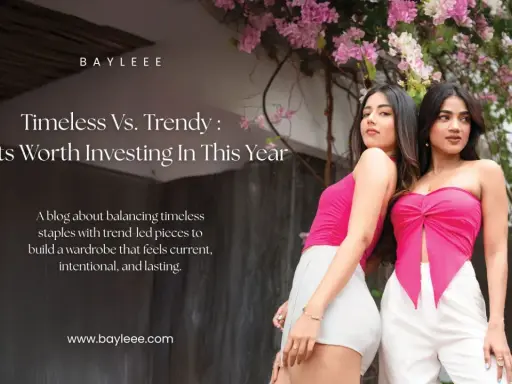 Two women showcase modern fashion couture, one in a pink tube top and white shorts, the other in a pink knotted top and white pants, against a backdrop of pink flowers.