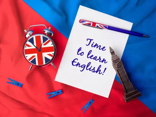 Budzik z flagą UK, długopis i napis "Time to learn English!" na tle brytyjskich barw. Czas na naukę!