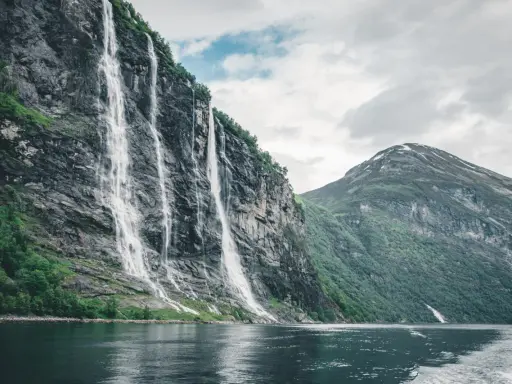 Siedem Sióstr, wodospad w Geirangerfjordzie, to jedno z najpiękniejszych miejsc w Norwegii. Woda spływa kaskadami po skalnej ścianie, tworząc spektakularny widok.