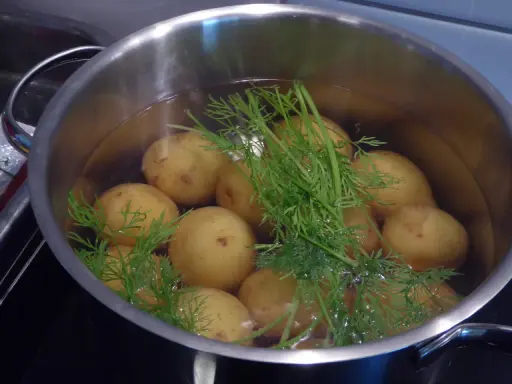 En gryta med dillkokt potatis i vatten. Snart redo att serveras med smör och mer dill.