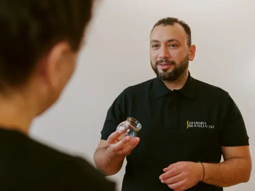 Terapeuta pokazuje bańkę, wyjaśniając, gdzie stawiać bańki na kaszel.