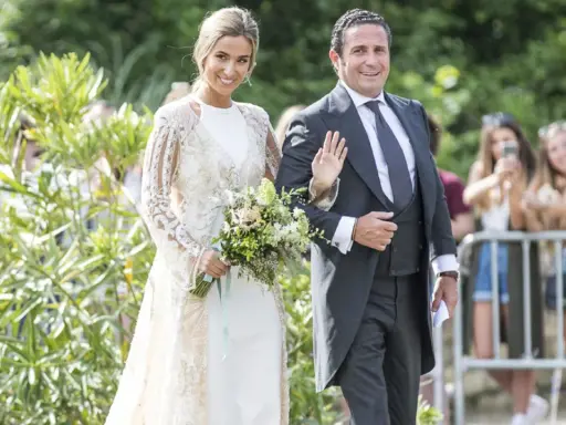 Novia y novio sonríen en la boda de María Pombo. Ella lleva un vestido blanco con encaje y él un traje gris.