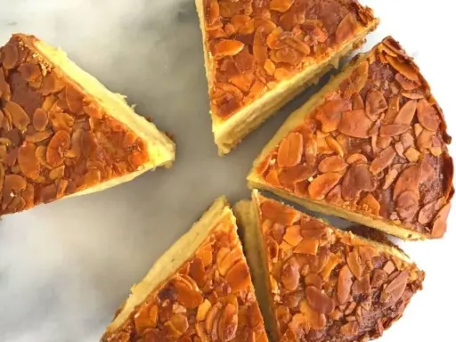 Tranches d'un délicieux **nid d'abeille gâteau** aux amandes grillées, disposées en cercle sur un fond marbré.