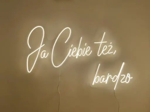 Neonowy napis "Ja ciebie też bardzo" rozświetla ścianę, tworząc ciepłą atmosferę.