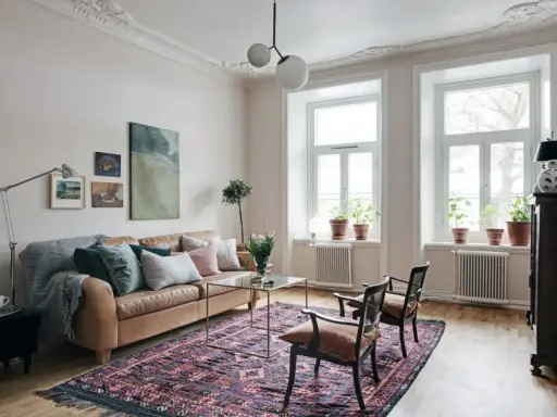 En vardagsrumsinredning som visar vad bohemisk betyder: en brun skinnsoffa, en stor mönstrad matta, konst och växter.